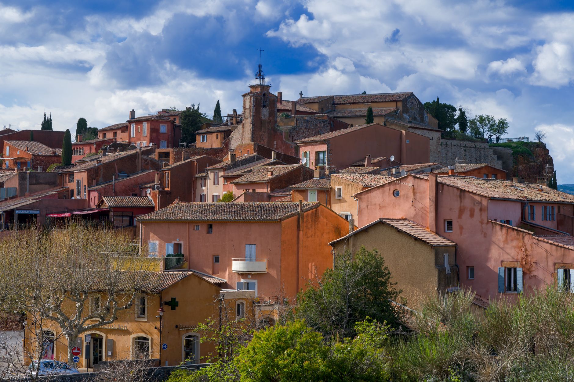 Vue panoramique du village ocre de Roussillon, Provence, sous un ciel vibrant.
